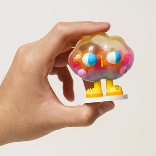 Hand holding a colorful toy figure on a plain background