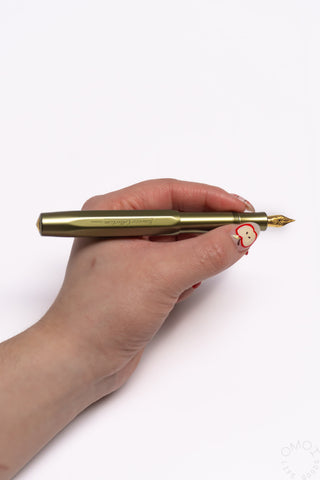 Olivine green fountain pen held in hand, gold nib exposed