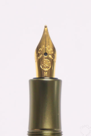 Gold fountain pen nib close-up on an olivine green Kaweco AL Sport pen