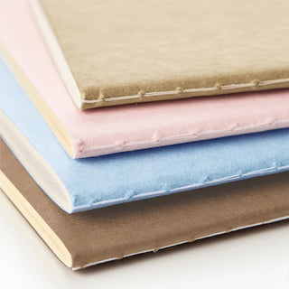 Stacked B6 2mm grid notebooks showing page edges in brown, pink, and blue
