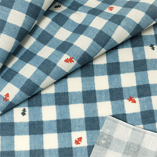 Close-up of blue and white checkered fabric with red and black goldfish patterns.