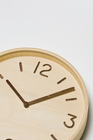 Close-up of natural wood wall clock face with black hands and numerals