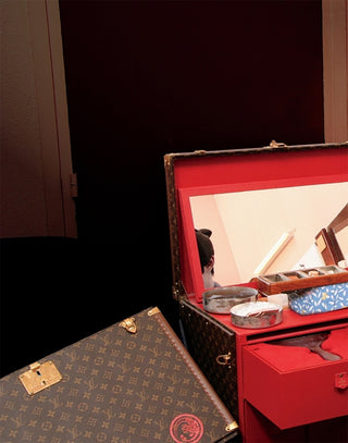 Open red suitcase with contents inside, next to a patterned brown suitcase.