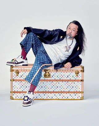 Person sitting on a patterned suitcase with a neutral background