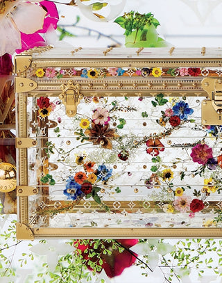 Decorative suitcase with floral patterns and gold accents on a white background