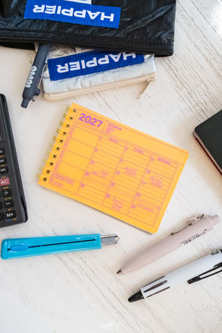 Neon orange mini calendar with stationery items scattered around