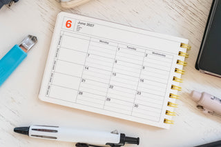 Close up of notebook calendar with stationery items scattered around