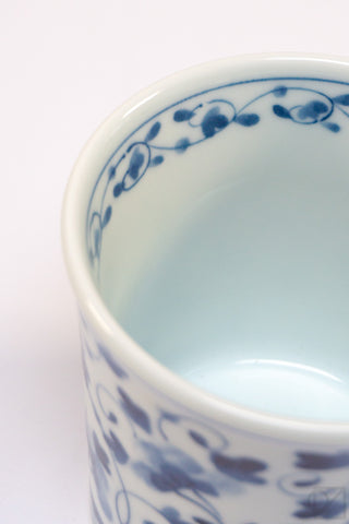 Close-up of a ceramic cup with blue floral patterns on a white background