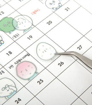 Calendar with cartoon character stickers being placed with tweezers