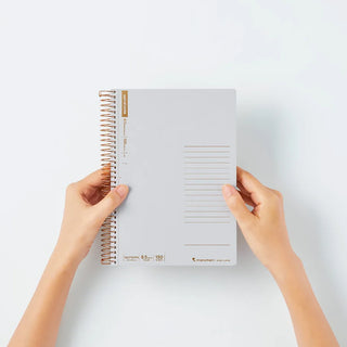Person holding a spiral-bound notebook on a light gray background