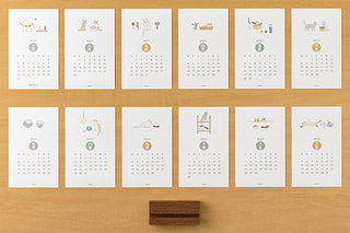 Set of 2027 cat stand calendar cards arranged in rows, with wooden base at center