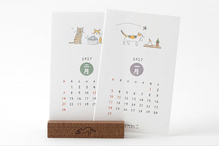Two-panel 2027 cat stand calendar with monthly date grids, displayed upright on wooden base