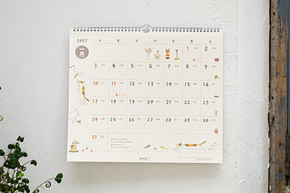 Midori 2027 wall calendar hanging on wall with cat illustrations and date grid