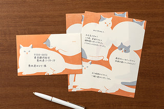 Envelope and letter pad with cat designs with writing on the pages on a wooden table