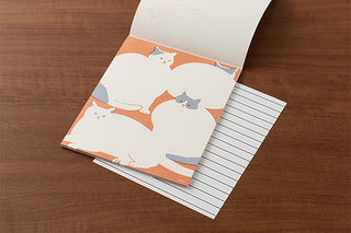 Letter set page open with cat illustration and lined sheet underneath on a wooden background
