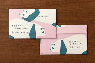 Two envelopes with panda designs and writing on a wooden surface