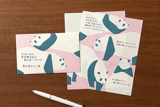 Envelope and letter pad with panda designs with writing on the pages on a wooden table