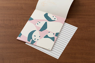 Letter set page open with panda illustration and lined sheet underneath on a wooden background
