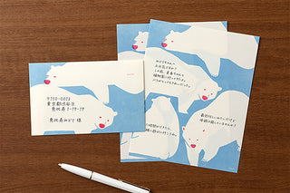 Two pages with writing with polar bear illustrations on a wooden surface next to matching envelopes