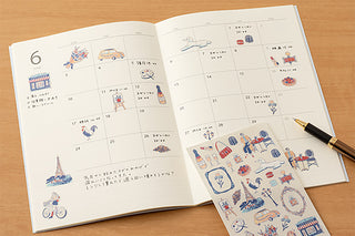 Open planner with illustrated stickers on a wooden surface