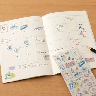 Open planner with stickers on a wooden surface