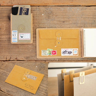 Brown kraft envelope with flap closure and decorative tags; includes other envelopes in set.