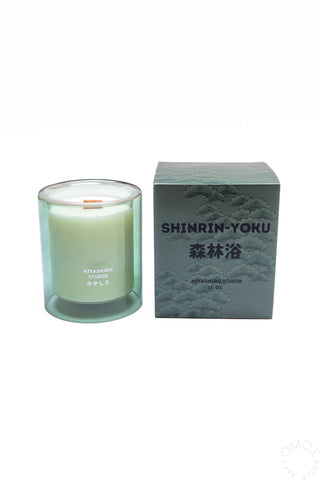 Shinrin-Yoku candle in a glass container next to packaging on a white background