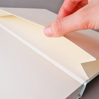 Hand opening a hard cover dot grid notebook, with inner pages exposed