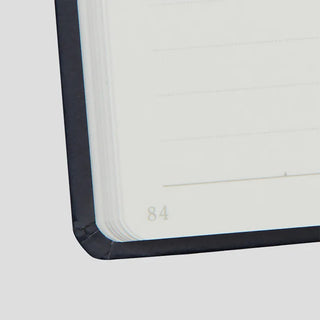 Navy hard cover notebook corner, page edge with printed “84”