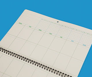 Spiral-bound planner with grid layout on a blue background