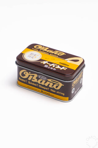 Natural rubber band tin with O'BAND branding, rectangular metal storage case.