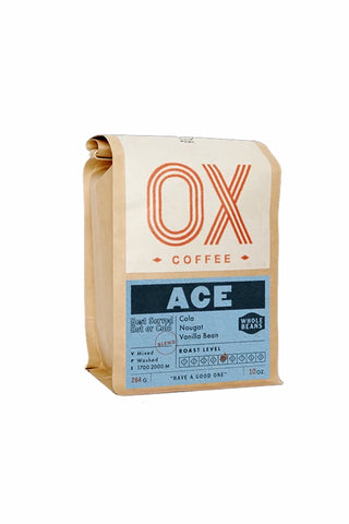 A 10oz bag of OX Coffee Ace Roasted Bean on a solid white background. The bag is made of kraft paper with a top label featuring a large orange 'OX' logo and a blue label below with the text 'ACE'.