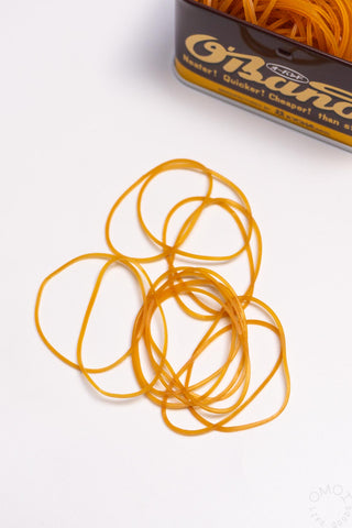 Loose orange natural rubber bands in curled loops.