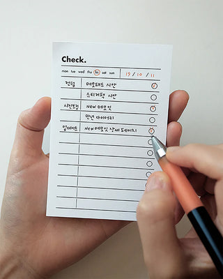 Person holding and writing on check list memo pad with days of the week and check boxes