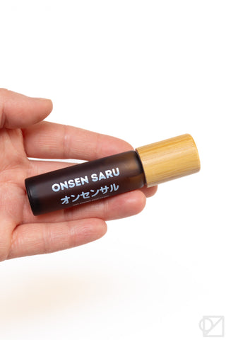 Hand holding a onsen saru skin scent on a white background