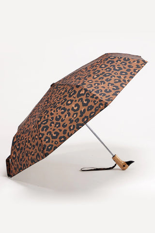 Leopard print umbrella with wooden duck head handle opened on a light background