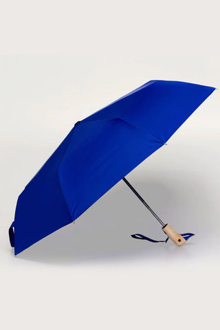 Royal blue umbrella with a duck shaped wooden handle opened on a light background