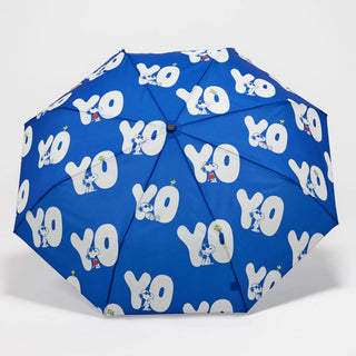 Blue umbrella with white 'YO' and Snoopy pattern on a light gray background
