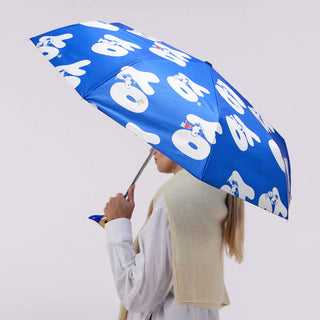 Person holding a blue umbrella with white Yo text and Snoopy pattern against a light gray background