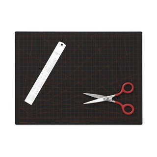 Black cutting mat with a ruler and scissors on a white background