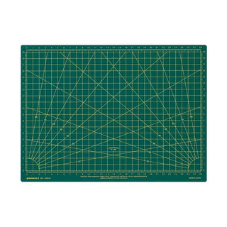 A green cutting mat with yellow grid lines, angle guides, and measurement markings, shown flat against a white background.