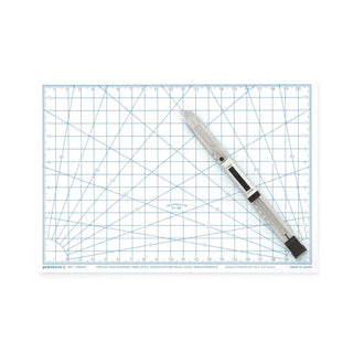 White and blue cutting mat with x-acto knife on it
