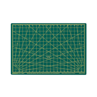 A green cutting mat with yellow grid lines, angle guides, and measurement markings, shown flat against a white background.