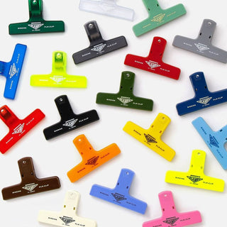 A collection of colorful binder clips in various solid colors displayed on a white background.