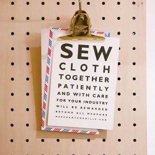 Gold binder clip holding a paper note on a pegboard backdrop