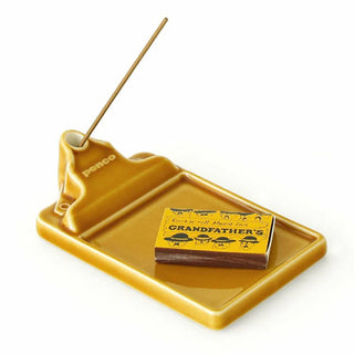 Brown incense holder with a stick and a box of matches on a white background