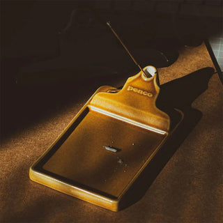 Brown ceramic incense holder with incense stick lit on a dark background