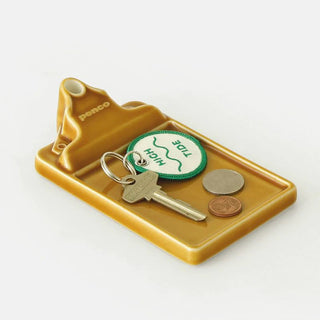 brown ceramic tray as a key holder with a keys and loose chain on a light background