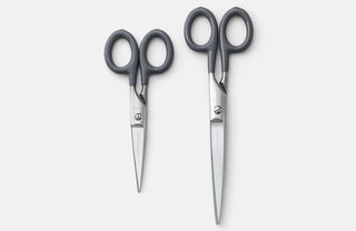 Small stainless steel scissors with dark gray handles, two pairs with pointed blades.