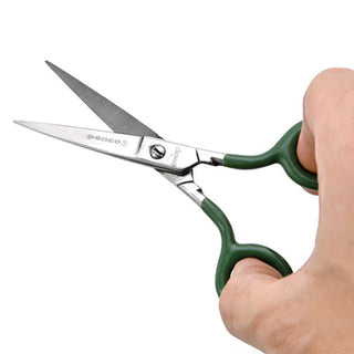 Small stainless steel scissors with green handles held in a hand, showing blades.